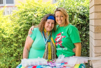 Michelle and her support worker Cass smile with a display of Michelle's craft