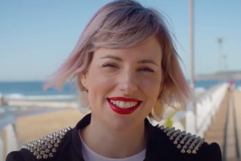 A close up of a woman with short hair and red lipstick smiling.