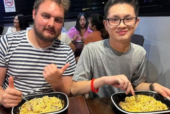 Two smiling young men having dinner together at a restaurant