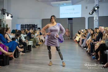 Smiling female model on a runway, posing on prosthetic legs