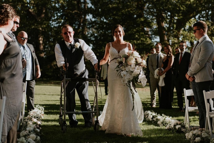 Steven walks daughter Hayley down the aisle at her outdoor wedding in glorious sunlight