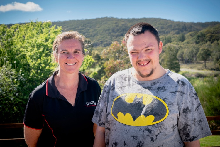 Christopher and his house team leader Leanne smile together in front of a scenic mountain view