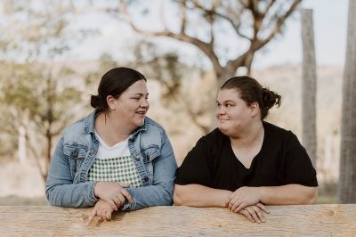 Tiffany and Angelica Hori lean on a fence and enjoy a conversation.