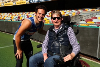 John and Brisbane Lions AFL player meet and smile on the ground of a football stadium