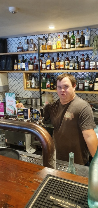 Ben stands behind the bar at The Happy Wombat