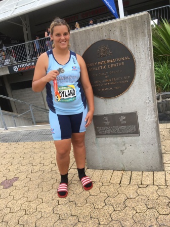 Rosie stands in front of the sydney international athletic centre with her medal