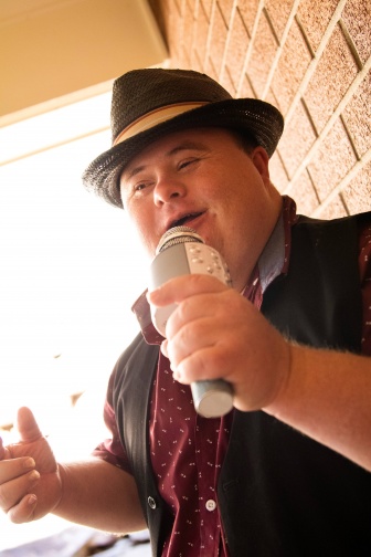 Stanley singing into a hand-held microphone wearing a smart black hat.
