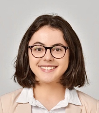 A young woman with shoulder length brown hair and round glasses.