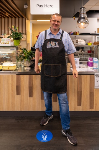 Dave is wearing an apron and standing in front of a cafe counter