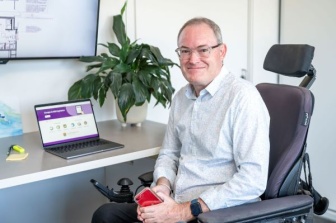 A man sitting at a desk with NDIS website open on screen
