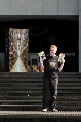 Liam standing outside on some steps with his book