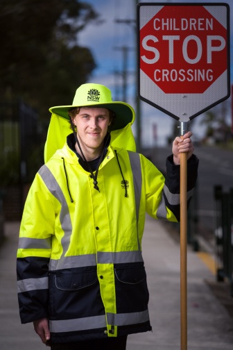 Man in high-visibility coat and hat, holding a STOP sign.