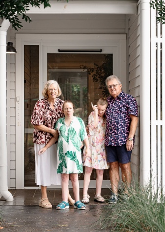 Twin sisters Ellen and Georgia, with their parents outside the front door of a house.