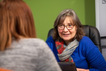 A woman sits at a desk opposite an NDIS participant