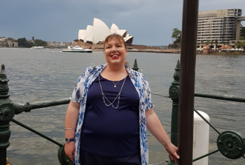 Female NDIS participant standing in front of the Sydney Opera House, smiling.