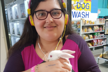 Female NDIS participant in her early 20s' cuddling a white rabbit.