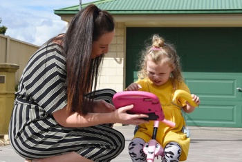 Sophia and her mum play outside, while Sophia communicates using the new device.
