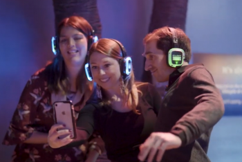 Gig Buddy participants and volunteers smile for a group selfie wearin neon silent disco headphones