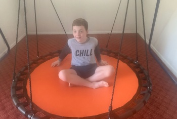 Charlie sits on his orange trampoline