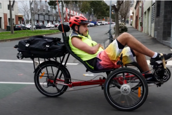 Tom riding his recumbent trike wearing high visibility clothes and helmet