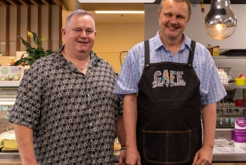 Cafe owner Mark stands next to Dave who is wearing an apron