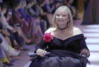 Carol Taylor on the runway, wearing a black, off the shoulder gown