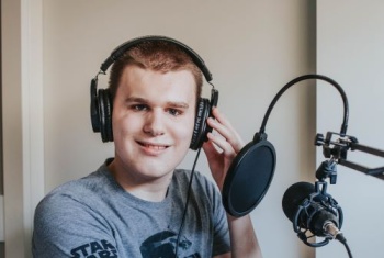 Sam in front of a microphone with some headphones on. 
