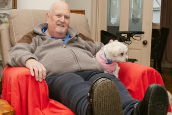 Smiling man sitting in armchair with pet dog